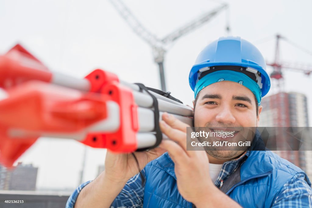 Mixed race worker carrying metal on construction site