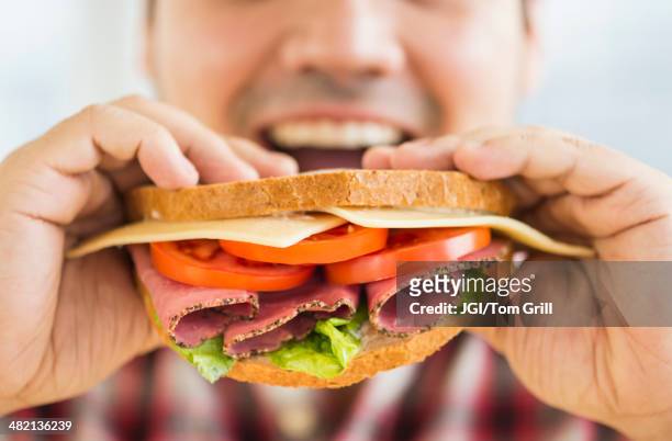 mixed race man eating sandwich - brot mund stock-fotos und bilder