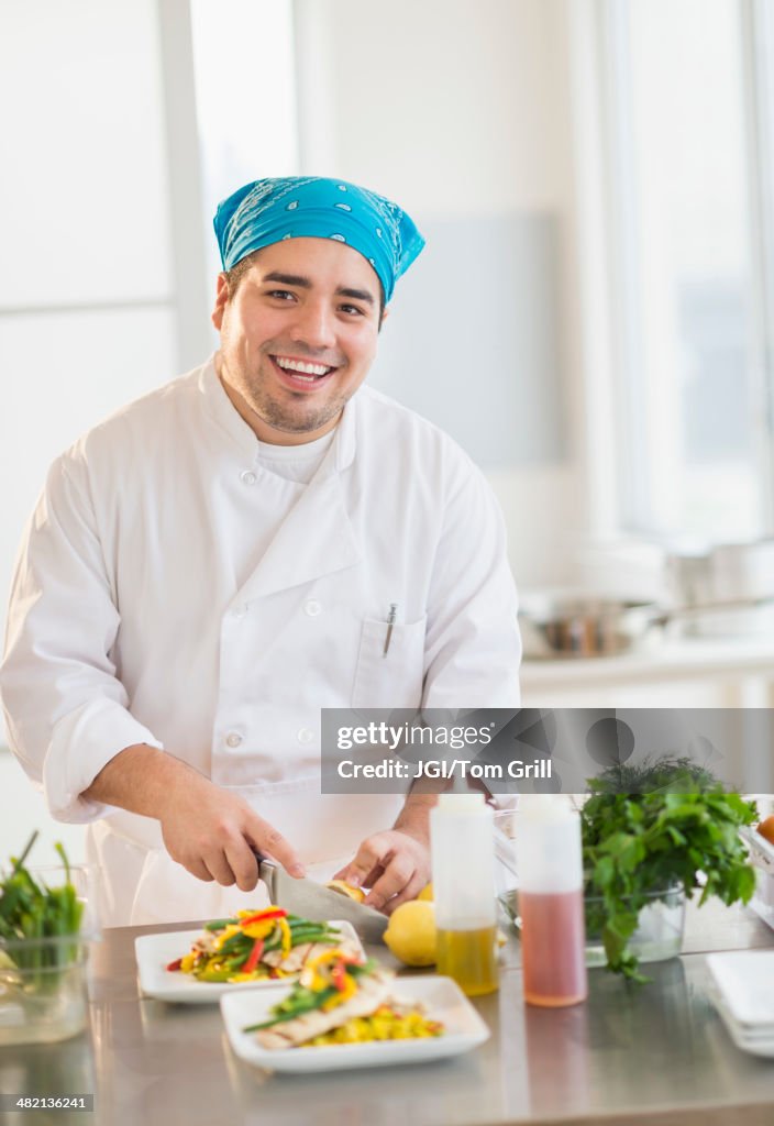 Mixed race chef plating food in restaurant