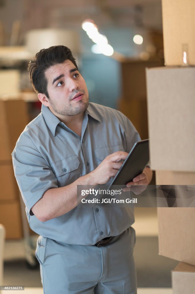 Mixed race worker counting boxes in warehouse