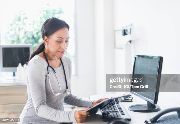 african american doctor looking down at clipboard - doctor looking down stock pictures, royalty-free photos & images