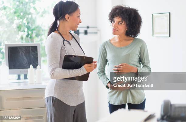 african american doctor talking to pregnant woman - pregnant woman at doctor stock-fotos und bilder