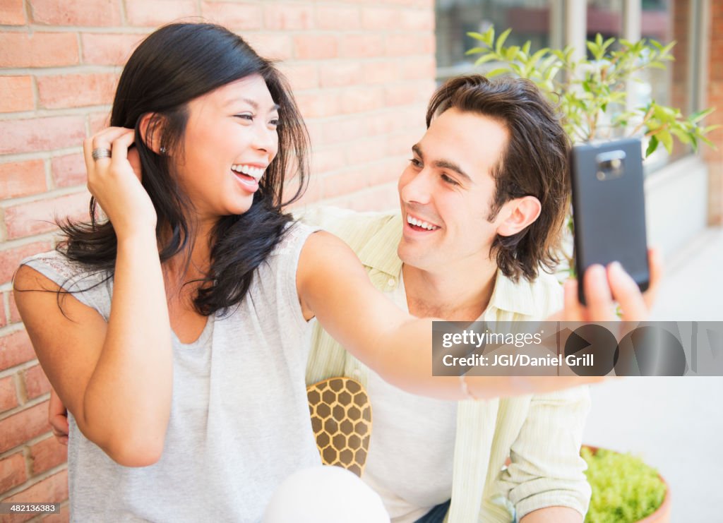 Couple taking self-portrait at sidewalk cafe