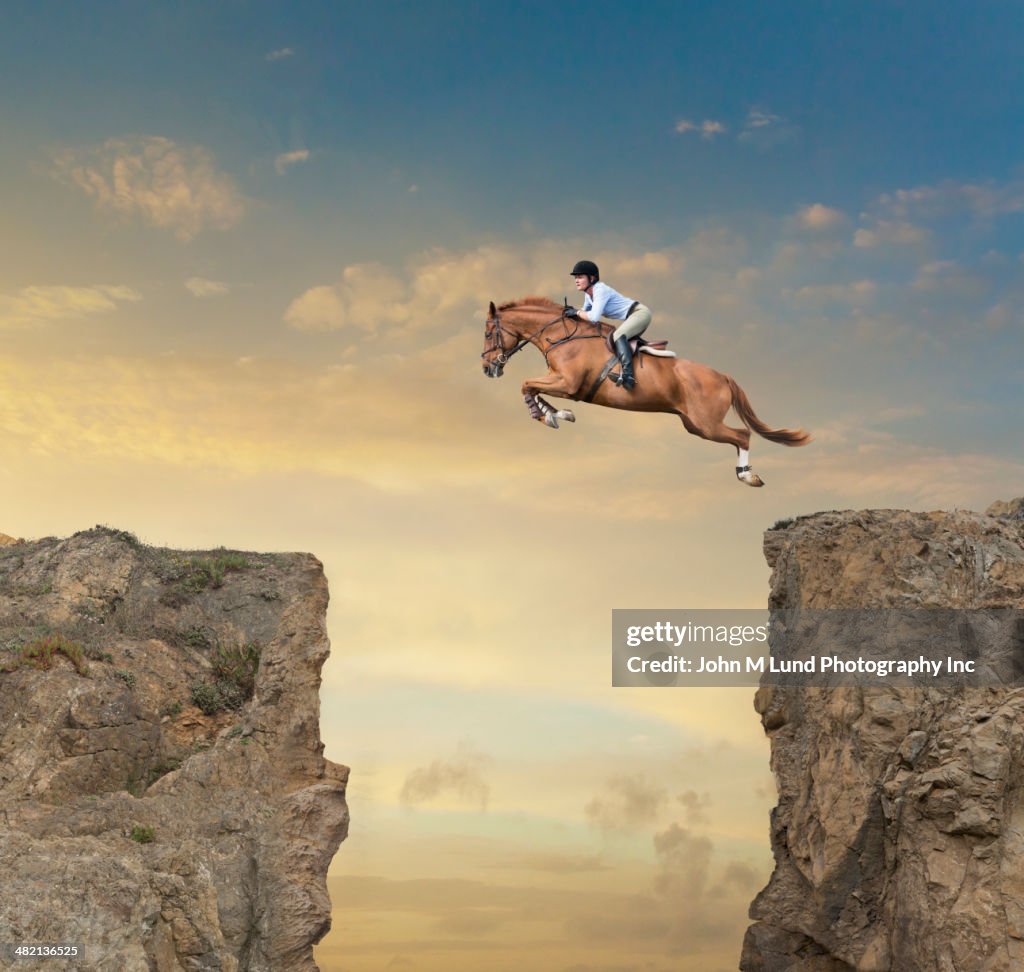 Caucasian jockey jumping canyon on horse