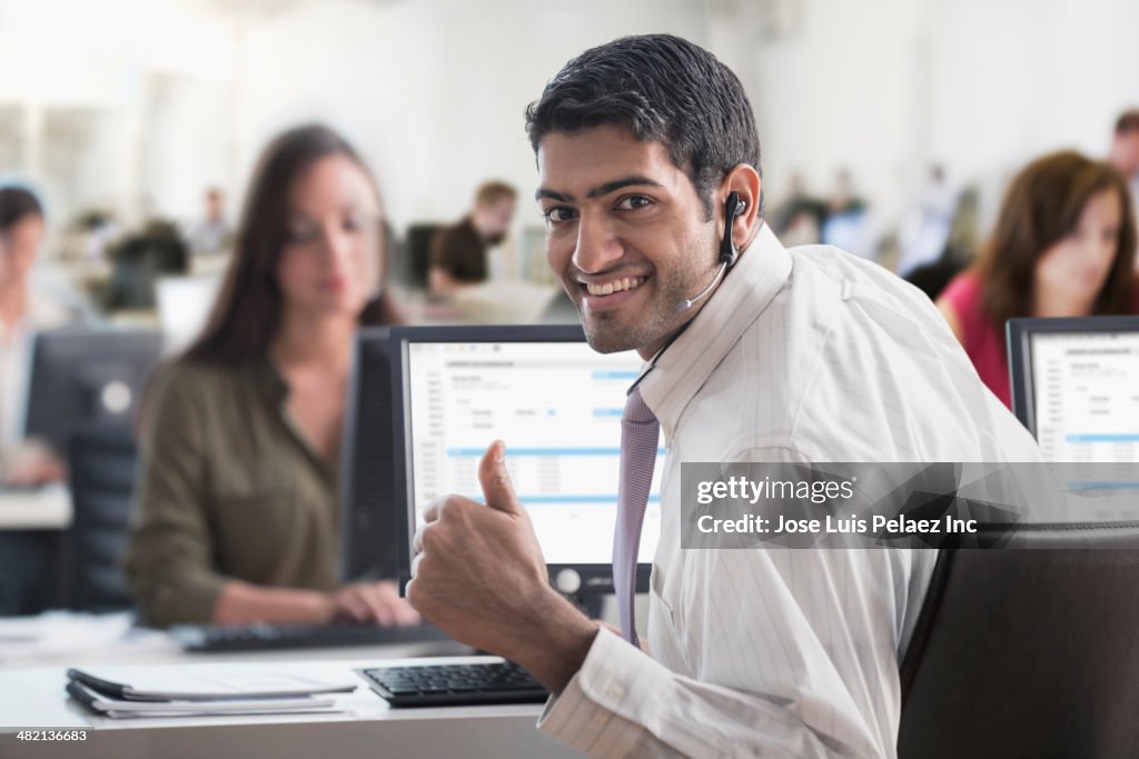 Indian businessman giving thumbs up in office