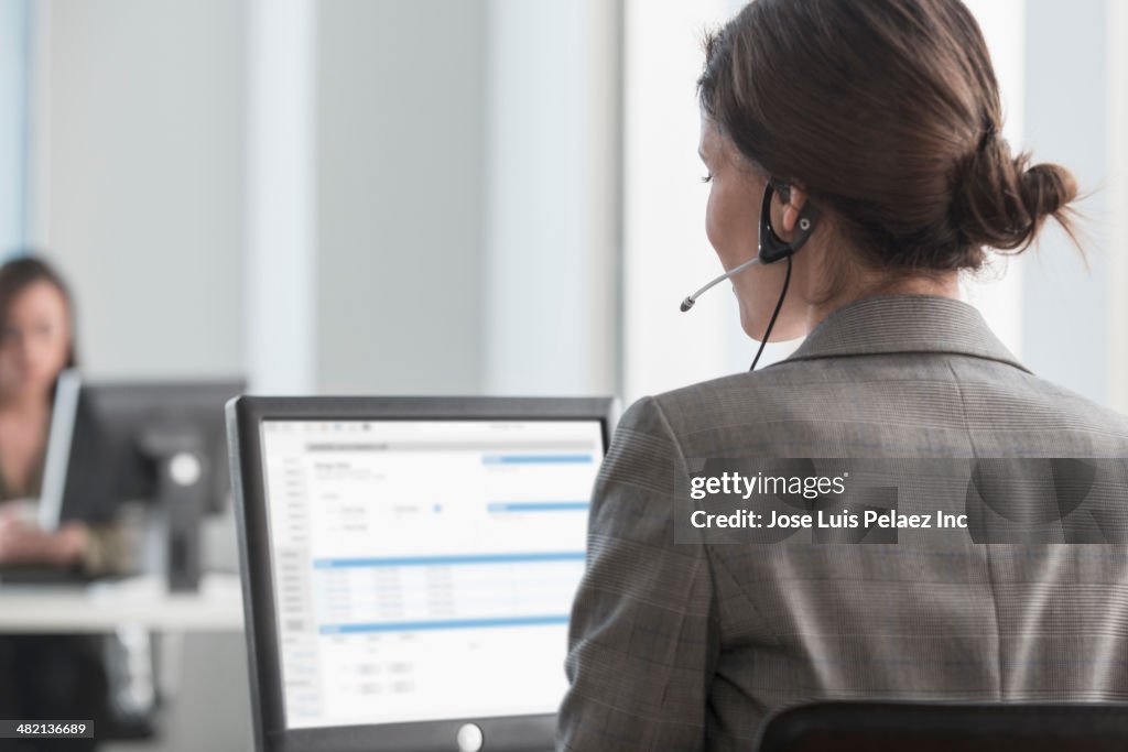 Businesswoman talking on headset at desk