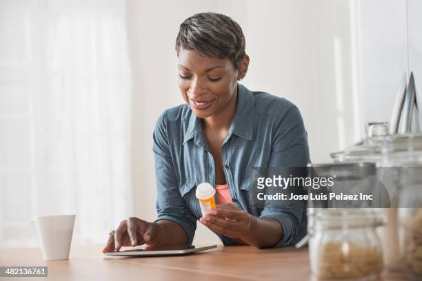 african american woman researching prescription bottle - prescription medicine stock pictures, royalty-free photos & images
