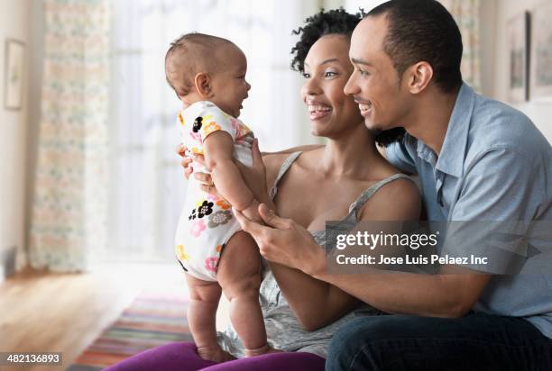 couple playing with baby in living room - mum dad and baby stock pictures, royalty-free photos & images