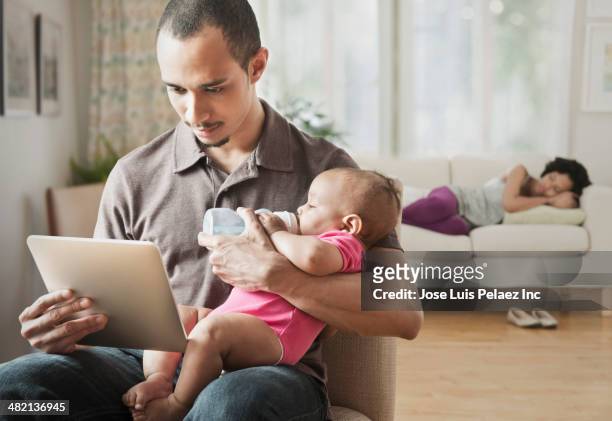 father feeding baby and using digital tablet - woman taking a nap stock-fotos und bilder