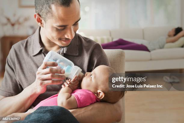 father feeding baby in living room - baby bottle foto e immagini stock