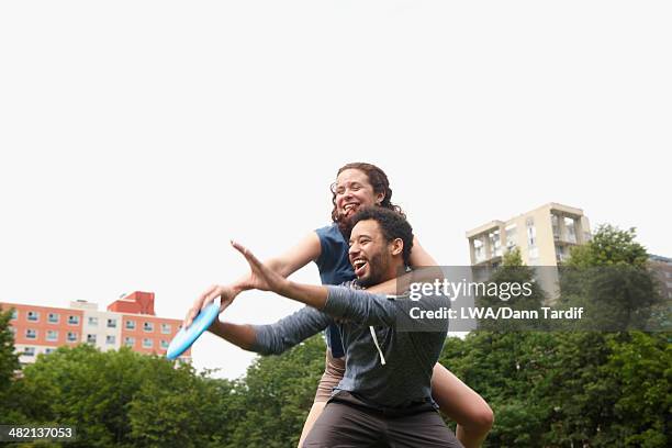 couple playing with plastic disc in urban park - flying disc stock pictures, royalty-free photos & images