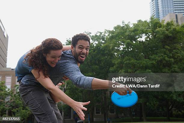 couple playing with plastic disc in urban park - lanzar término deportivo fotografías e imágenes de stock