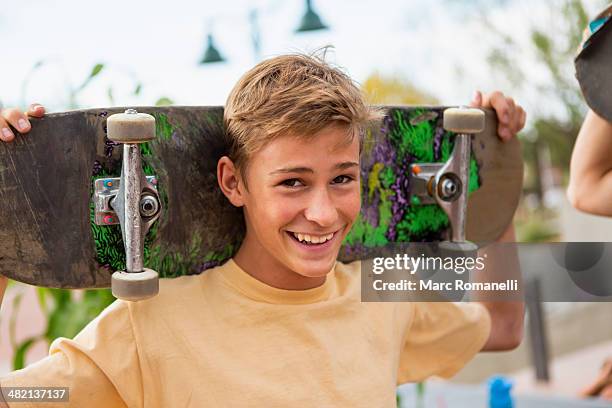 caucasian boy holding skateboard outdoors - 14 years old blonde boy stock pictures, royalty-free photos & images