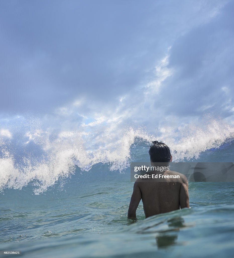 Young Man in Water Facing Big Wave