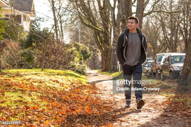 mixed race man walking on suburban street - fall in seattle fotografías e imágenes de stock