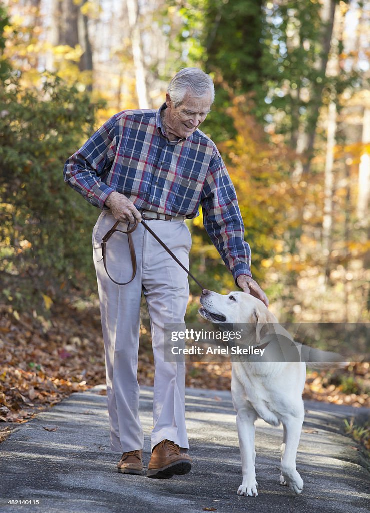 Senior Caucasian man walking dog in park