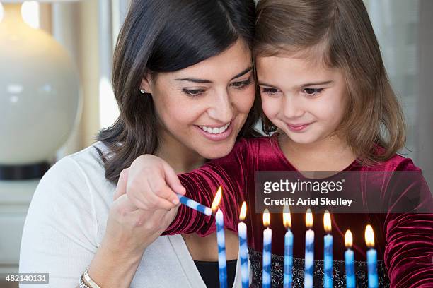 mother and daughter lighting hanukah menorah - two young arabic children only indoor portrait stock-fotos und bilder