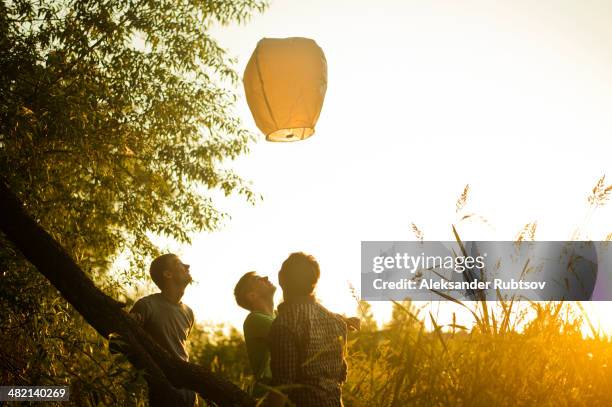 caucasian men launching floating lantern outdoors - releasing lanterns stock pictures, royalty-free photos & images