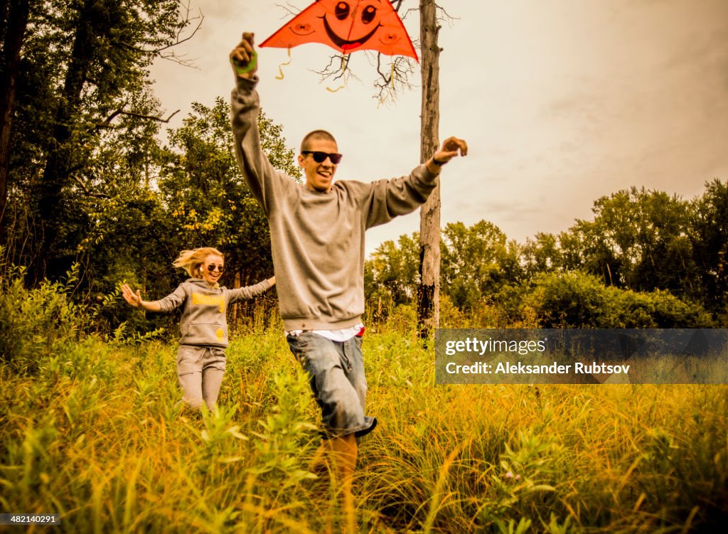 Caucasian couple flying kite in rural field