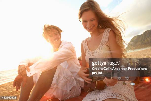 caucasian woman playing ukulele for boyfriend on beach - couple singing stock pictures, royalty-free photos & images