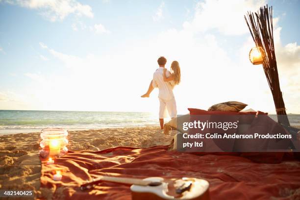 caucasian man carrying girlfriend on beach - honeymoon 個照片及圖片檔