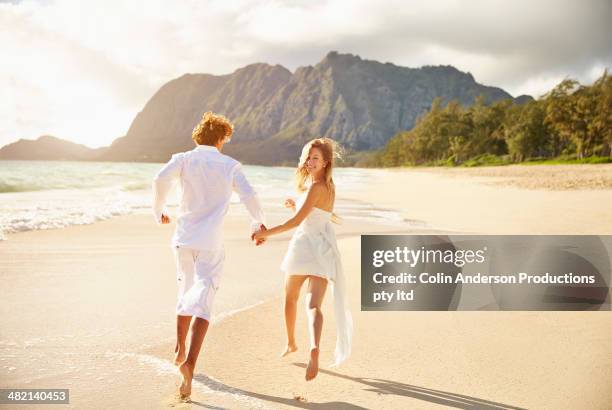 caucasian couple running on beach - honeymoon 個照片及圖片檔