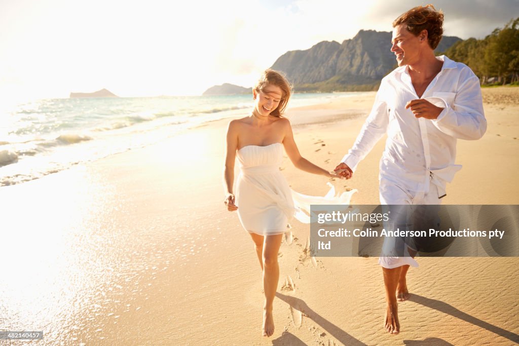 Caucasian couple running on beach