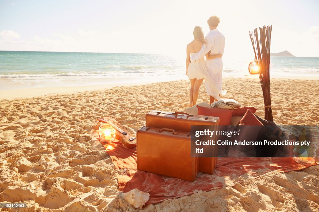 Caucasian couple with suitcases on tropical beach