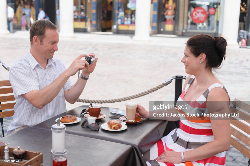 Couple taking photograph at sidewalk cafe