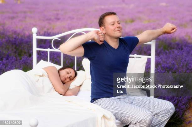 caucasian man waking in bed in lavender field - crecimiento estirón fotografías e imágenes de stock