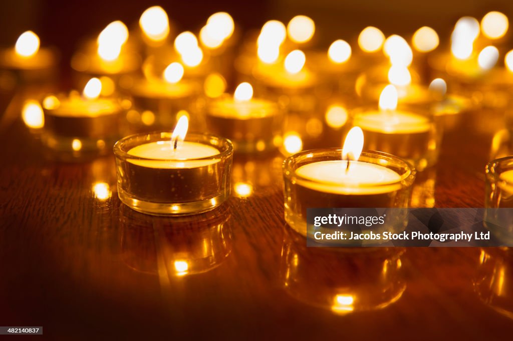 Close up of lit tea light candles on wooden table