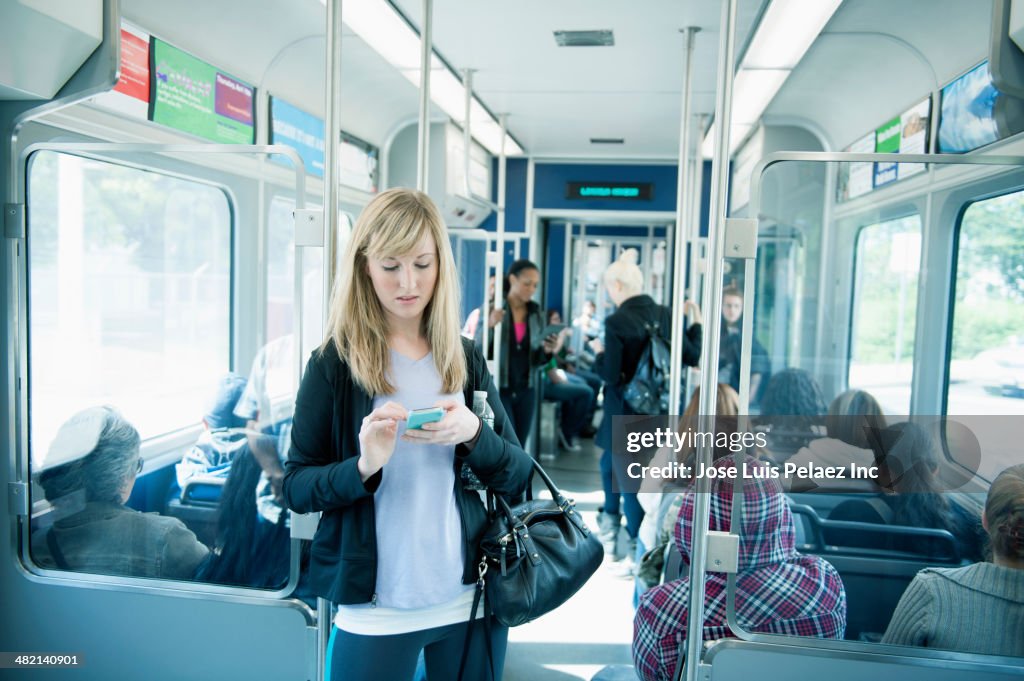 Caucasian woman using cell phone on train