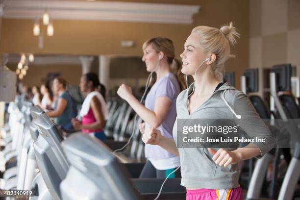 caucasian women exercising on treadmills in gym - トレッドミル　女性 ストックフォトと画像
