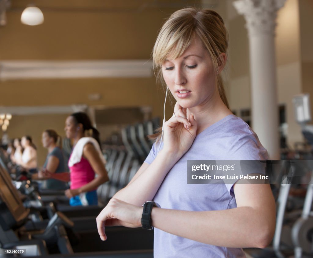 Caucasian woman checking pulse in gym