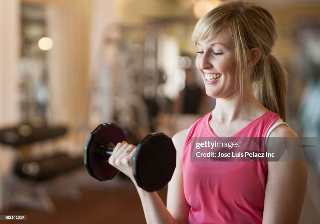 Caucasian woman lifting weights in gym