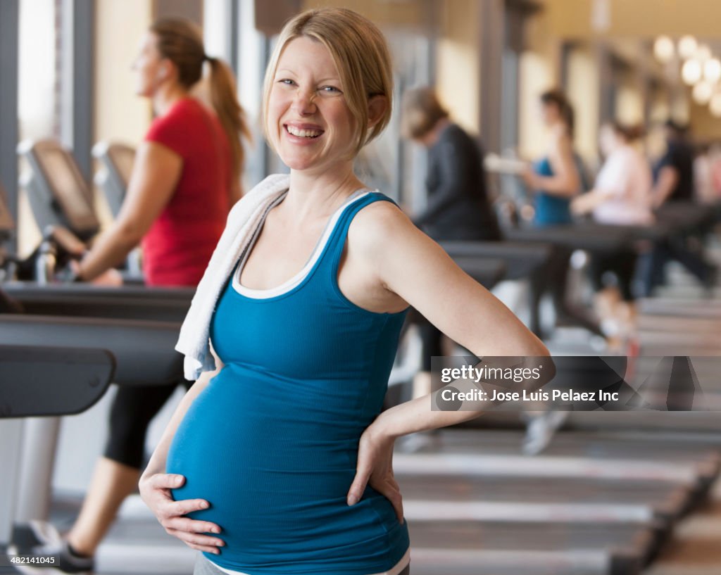 Pregnant Caucasian woman smiling in gym