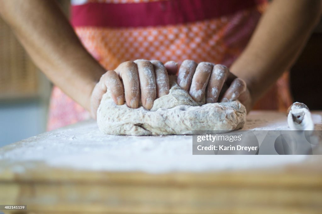 Mixed race woman kneading dough in kitchen
