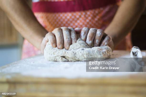 mixed race woman kneading dough in kitchen - kneading stock pictures, royalty-free photos & images