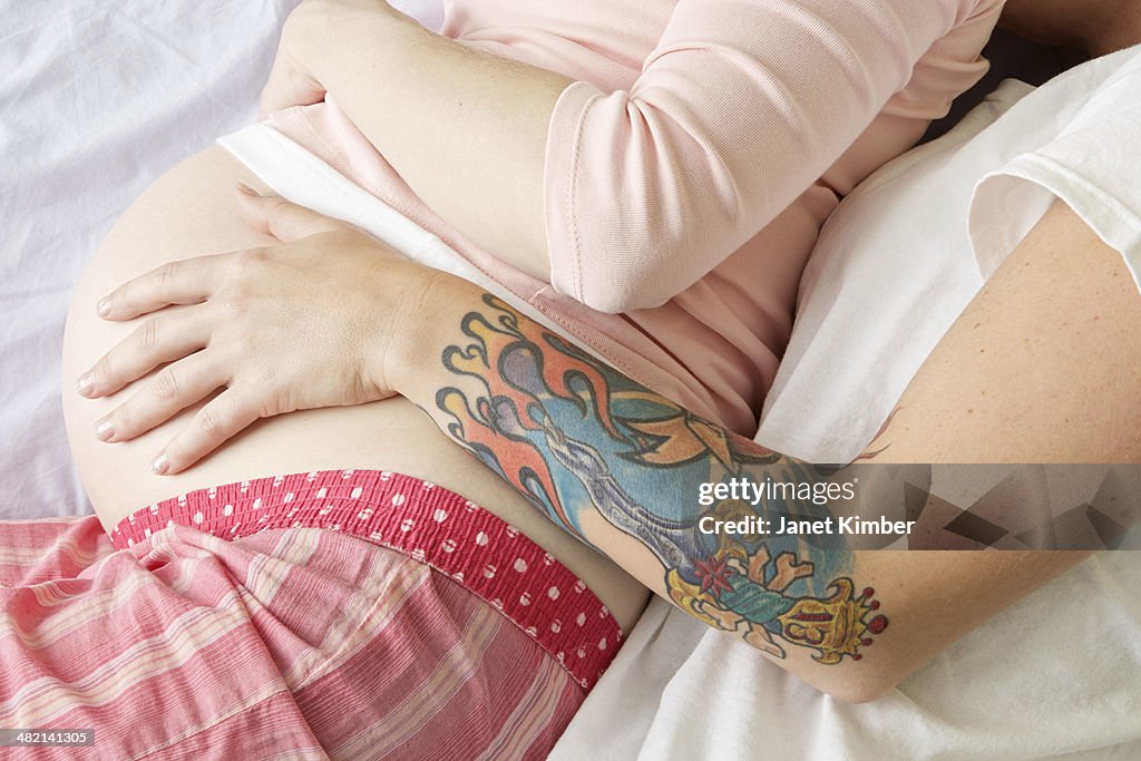 Caucasian lesbian couple holding pregnant belly