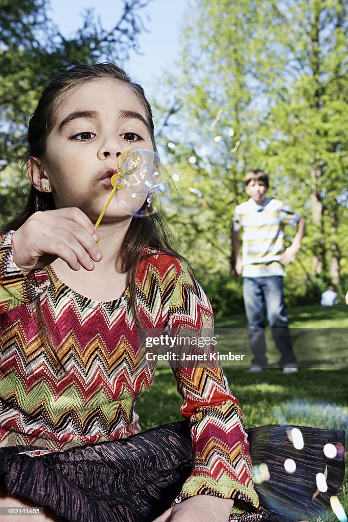 Caucasian girl blowing bubbles in park