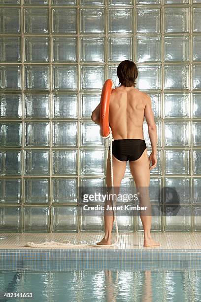 caucasian man holding life ring by pool - young men in speedos stock pictures, royalty-free photos & images
