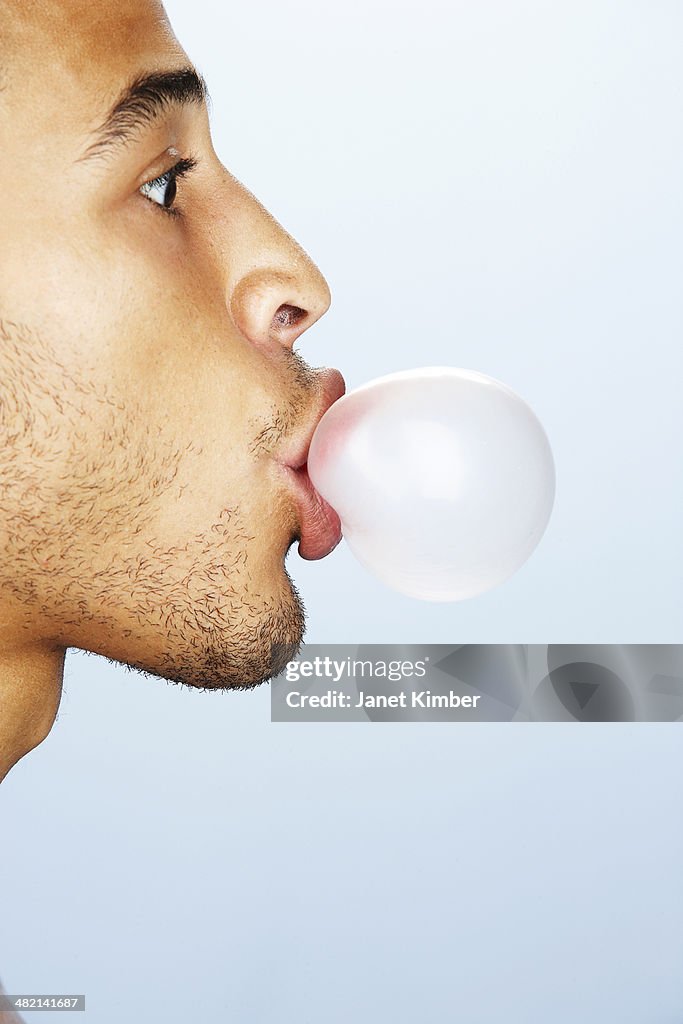 Mixed race man blowing bubble with gum