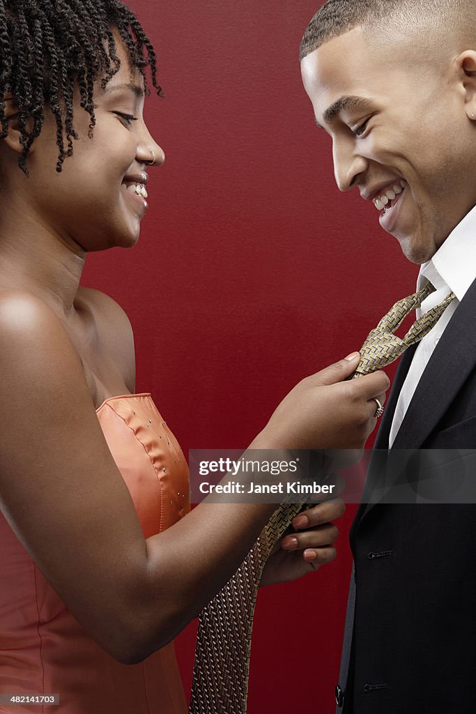 Woman in dress adjusting man's tie