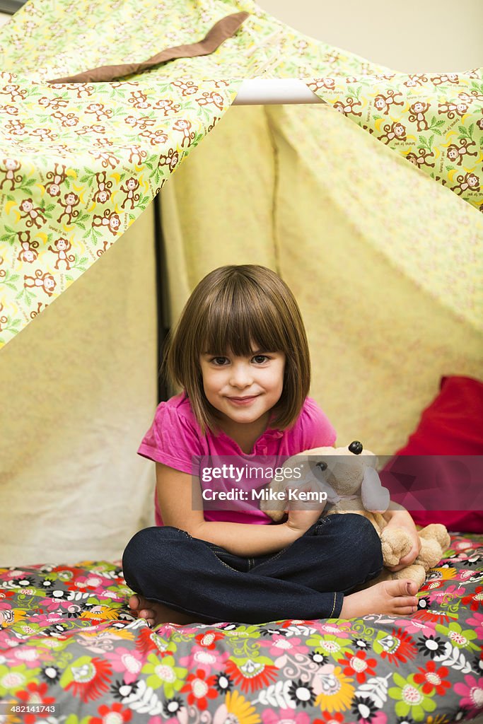 Caucasian girl sitting in blanket fort