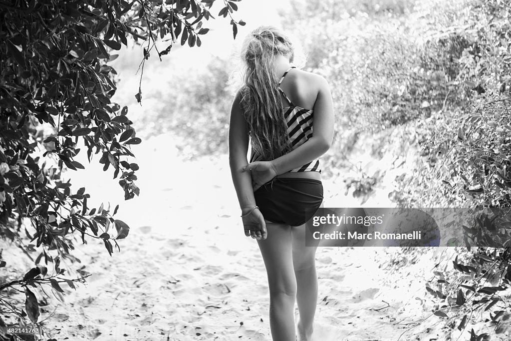 Caucasian girl in bathing suit walking on sandy path