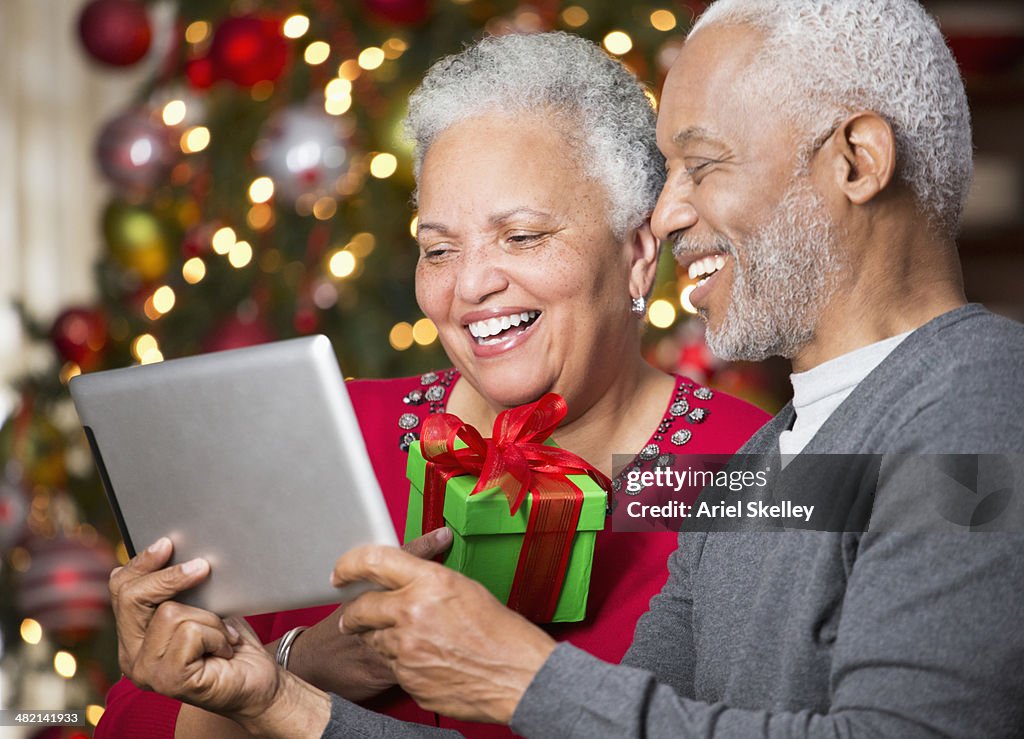 Black couple with Christmas gift using digital tablet