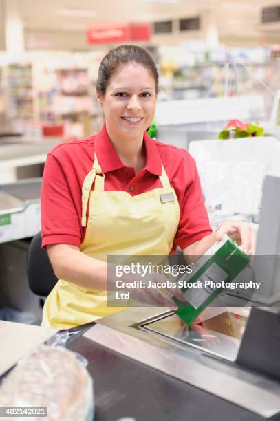 portrait of smiling hispanic woman working at grocery checkout - female supermarket stock-fotos und bilder