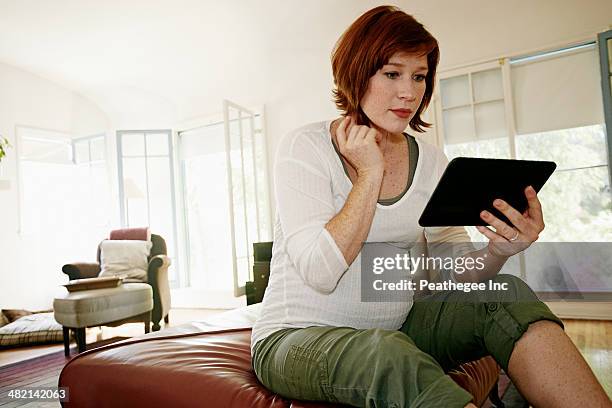 pregnant caucasian woman using digital tablet - pregnant redhead ストックフォトと画像