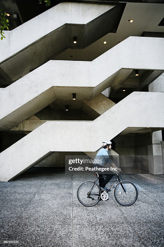 Caucasian businessman riding bicycle outside office building