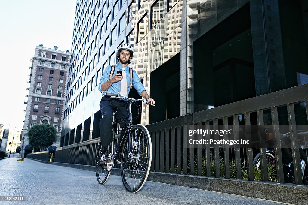 Caucasian businessman using cell phone on bicycle